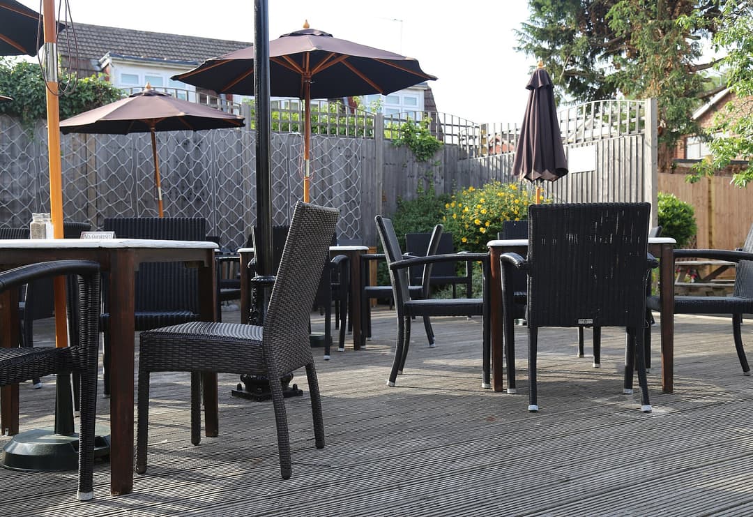 A raised wood decking with outdoor furniture in the beer garden of the Queen Victoria public house at  Theydon Bois, Essex, England